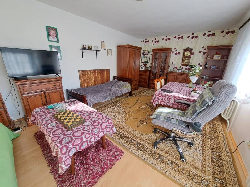 REZERVOVANÉ! Predáme 4-izb. rodinný dom, pozemok 1414 m2, Vráble - Izba v rodinnom dome s nábytkom, podlahou s dreveným dekorom a dekoračnými kobercami.