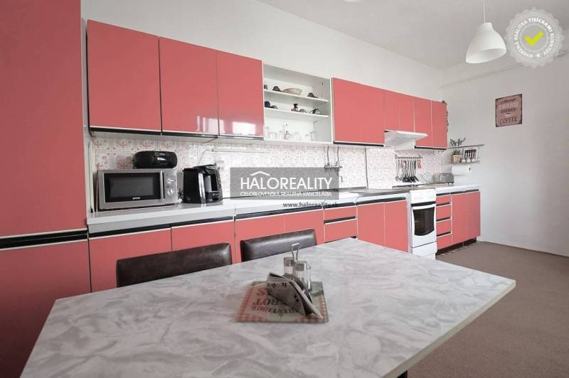 Predaj, rodinný dom Veľký Kýr, šesťizbový s garážou ... - Kuchyňa v rodinnom dome s ružovými skrinkami a bielym stolom.