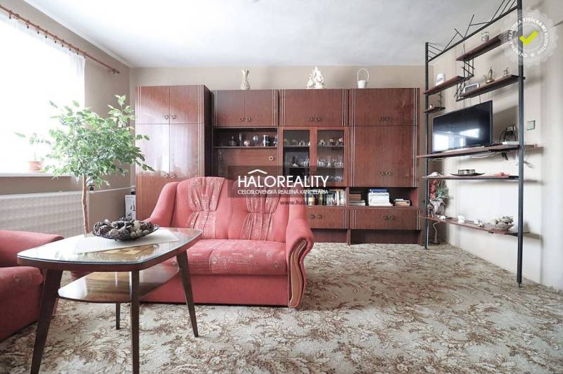 Predaj, rodinný dom Veľký Kýr, šesťizbový s garážou ... - Obývačka v rodinnom dome s červenou sedačkou a drevenou obývacou stenou.