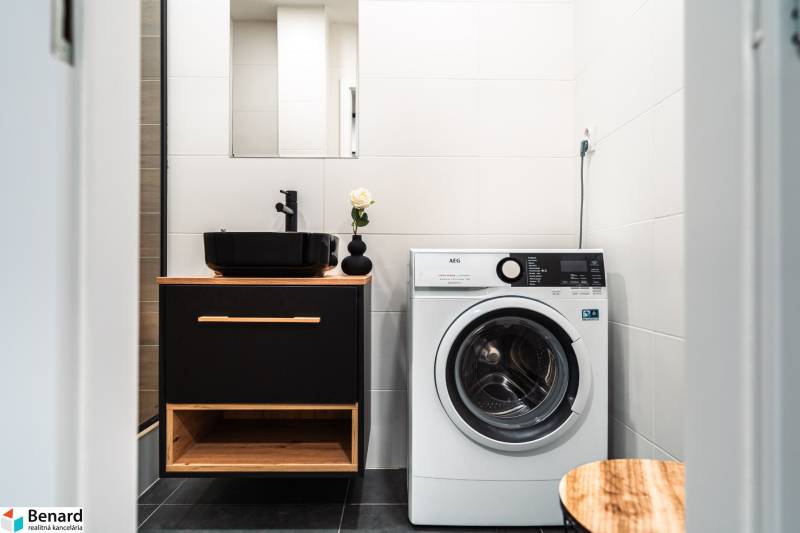 Na prenájom moderný 2-izbový byt  - Kúpeľňa v 2-izbovom byte s umývadlom, práčkou a čiernymi doplnkami.