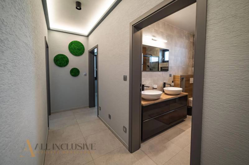 ALL INCLUSIVE I NOVOSTAVBA 4- IZBOVÝ RD SMART HOME - MOSTOVÁ (GA) - Chodba rodinného domu s kúpeľňou, obklady, umývadlá, zrkadlo a umelé dekorácie na stene.