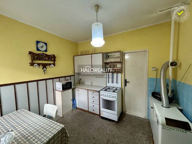 Predaj, rodinný dom Prievidza - EXKLUZÍVNE HALO REALITY - Kuchyňa v rodinnom dome so žltými stenami, bielym nábytkom a kobercovým povrchom.