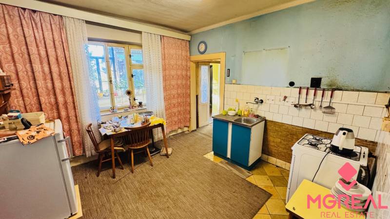 Na predaj 4-izbový rodinný dom v Brodzanoch – pozemok 1236 m² - Kuchyňa v rodinnom dome s jedálenským stolom, plynový sporák a umývadlo.