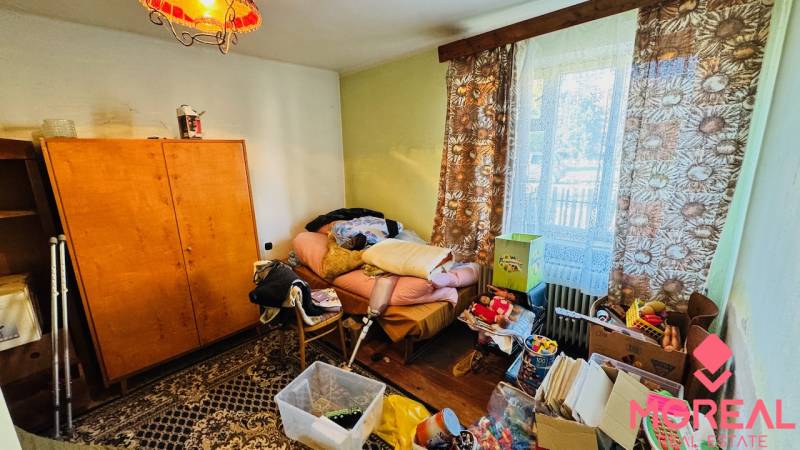 Na predaj 4-izbový rodinný dom v Brodzanoch – pozemok 1236 m² - Miestnosť v Rodinnom dome s neporiadkom, starým nábytkom a výhľadom cez okno.
