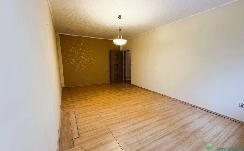 Výborná poloha, skvelá dispozícia – 3-izbový byt v Trebišove - Obývacia izba s podlahou s dreveným dekorom, luster a vzorovaná stena v 3-izbovom byte.