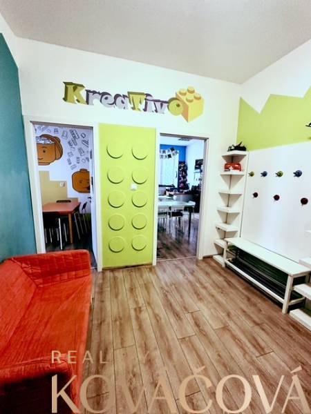 Prenájom kancelárskych priestorov, ul. Gen. M. R. Štefánika, Trenčín - Farebný interiér kancelárie s podlahou s dreveným dekorom a kreatívnym dizajnom vchodu.