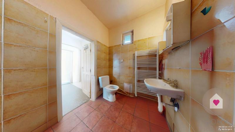 Veľký priestranný pozemok o rozlohe 7445 m2, Jelka  - Kúpeľňa so sanitou, umývadlom a radiátorom v rodinnom dome s dlaždicami.