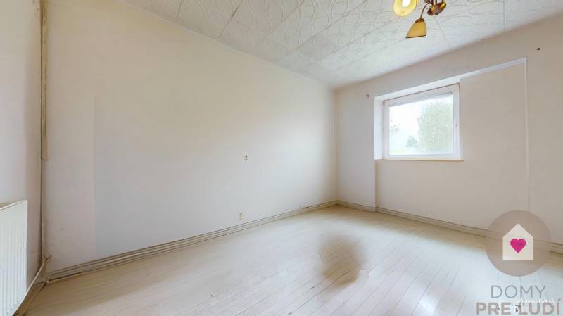 Veľký priestranný pozemok o rozlohe 7445 m2, Jelka  - Prázdna miestnosť v rodinnom dome s bielymi stenami a laminátovou podlahou.