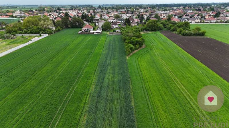 Veľký priestranný pozemok o rozlohe 7445 m2, Jelka  - Polia a domy v Jelke na Slanej doline, vidiecky charakter a rozľahlé zelené plochy.