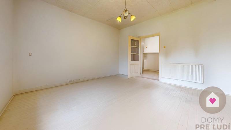 Veľký priestranný pozemok o rozlohe 7445 m2 s RD, Jelka  - Svetlá miestnosť v Rodinnom dome s drevenou podlahou a stropným svietidlom.