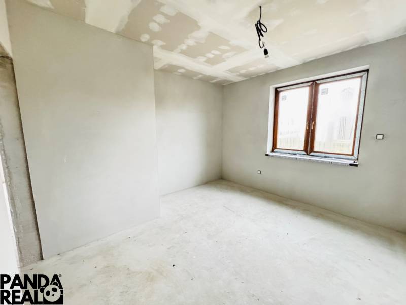 NOVOSTAVBA V CENE 3IZB BYTU - Neomietnutá miestnosť s veľkým oknom, podlaha s dreveným dekorom v rodinnom dome.