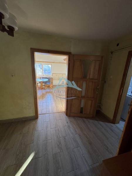 Skrytý raj v srdci prírody - Interiér rodinného domu s podlahou s dreveným dekorom a pohľadom do miestnosti.