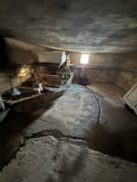 Skrytý raj v srdci prírody - Pivnica v rodinnom dome Demandíc s kamennými stenami a jednoduchým osvetlením.