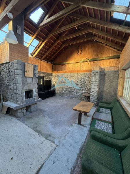 Skrytý raj v srdci prírody - Interiér rodinného domu s kamenným krbom a dreveným obložením.