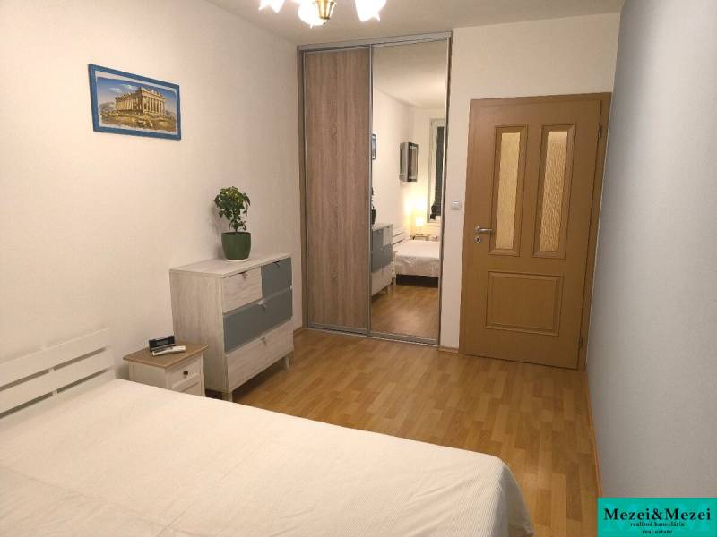 Na dlhodobý prenájom 2-izbový byt - kompletne zariadený, klimatizovaný - Spálňa v 2-izbovom byte s podlahou s dreveným dekorom, skrine so zrkadlom a obrazom.