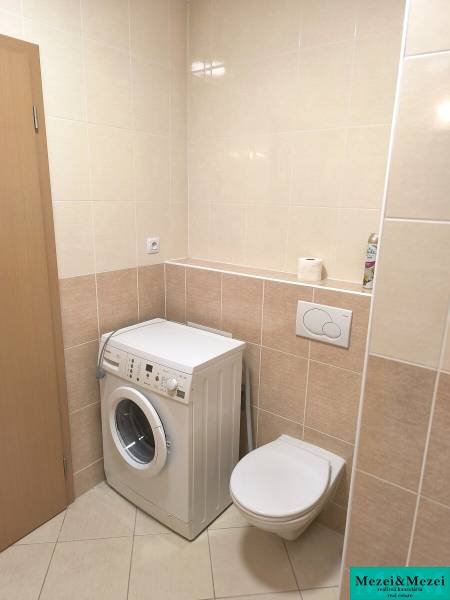 Na dlhodobý prenájom 2-izbový byt - kompletne zariadený, klimatizovaný - Kúpeľňa v 2-izbovom byte so svetlými dlaždicami, práčka a závesné WC.