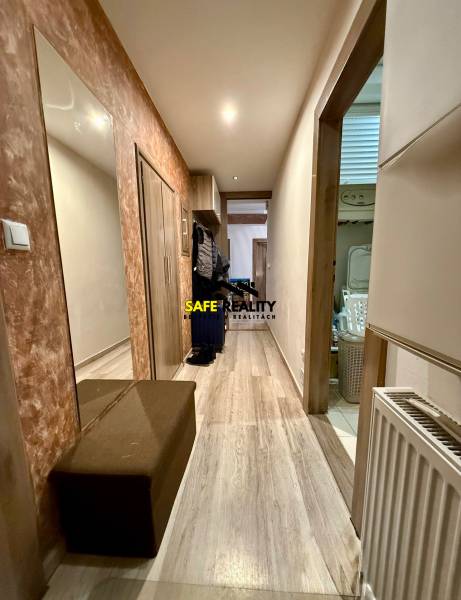 Dvojizbový byt, Považská Bystrica - Stred - Chodba v 2-izbovom byte s podlahou s dreveným dekorom, zrkadlom a botníkom.