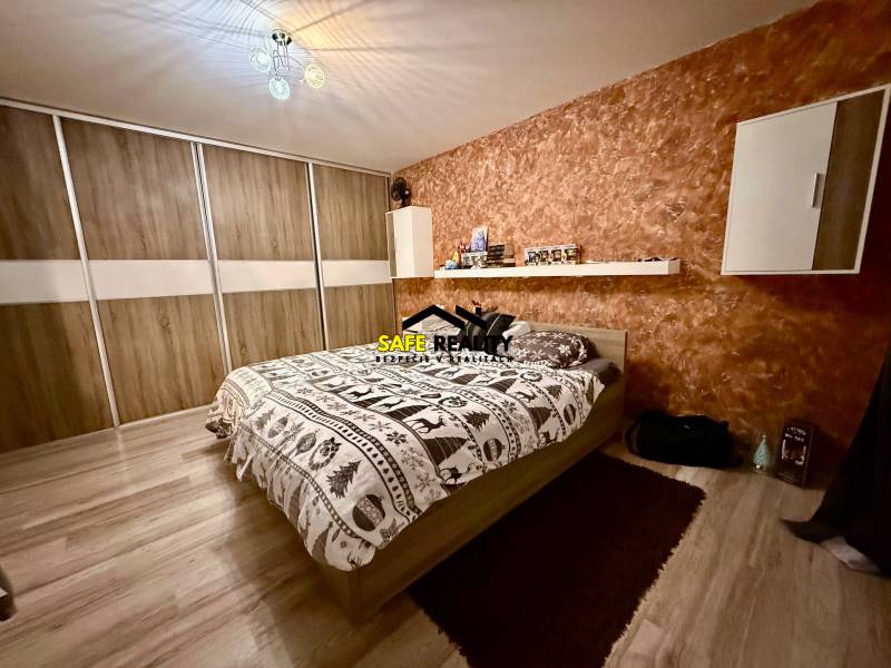 Dvojizbový byt, Považská Bystrica - Stred - Spálňa v 2-izbovom byte s posteľou, úložným priestorom a podlahou s dreveným dekorom.