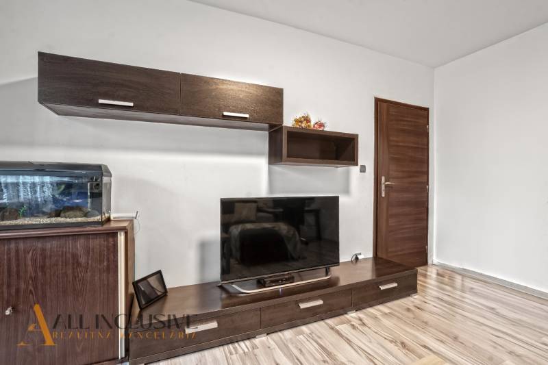 NA PREDAJ 3-IZBOVÝ BYT S PIVNICOU, SENEC - Obývacia izba v 3-izbovom byte s podlahou s dreveným dekorom a veľkou televíziou.