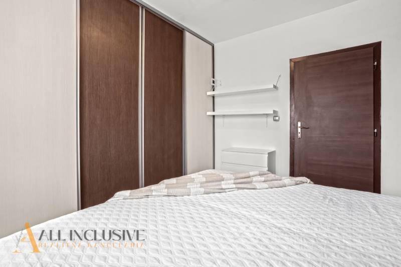 NA PREDAJ 3-IZBOVÝ BYT S PIVNICOU, SENEC - Spálňa v 3-izbovom byte s posteľou, vstavanou skriňou a minimalistickými policami.