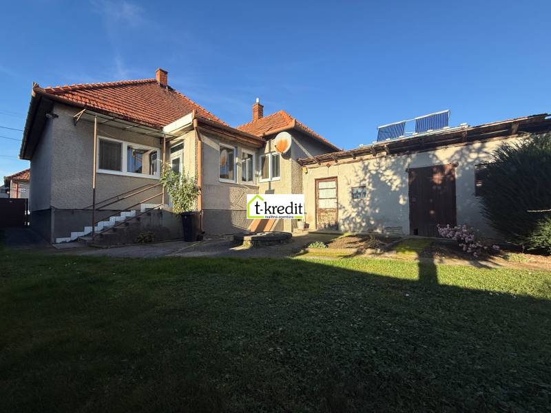 PREDAJ - RODINNÝ DOM - MACHULINCE - Rodinný dom v Machulinciach so záhradou a prístavbou, na modrej oblohe slnečný deň.