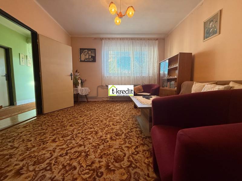 PREDAJ - RODINNÝ DOM - MACHULINCE - Obývacia izba v rodinnom dome s kobercovou podlahou, nábytkom a záclonami.