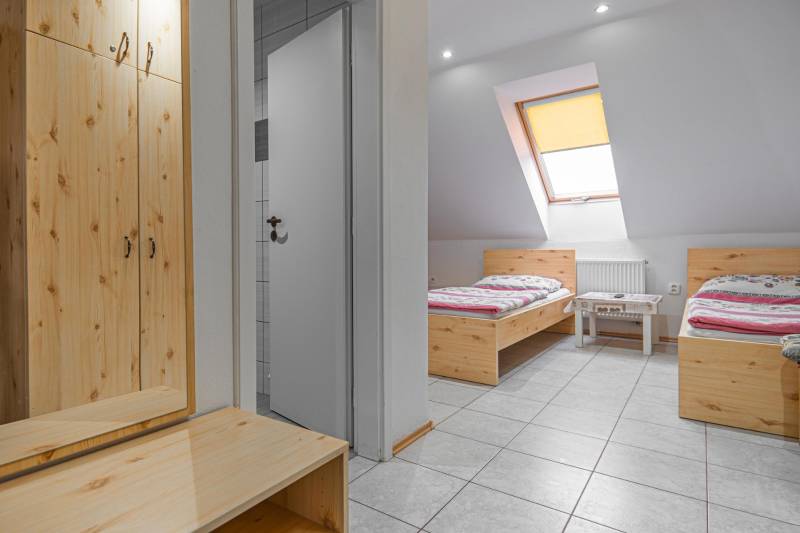 Predaj Exkluzívna ponuka elegantného penziónu s hostincom - Interiér izby Hotely a penzióny s dvoma posteľami a šatníkom, podlaha s dreveným dekorom.