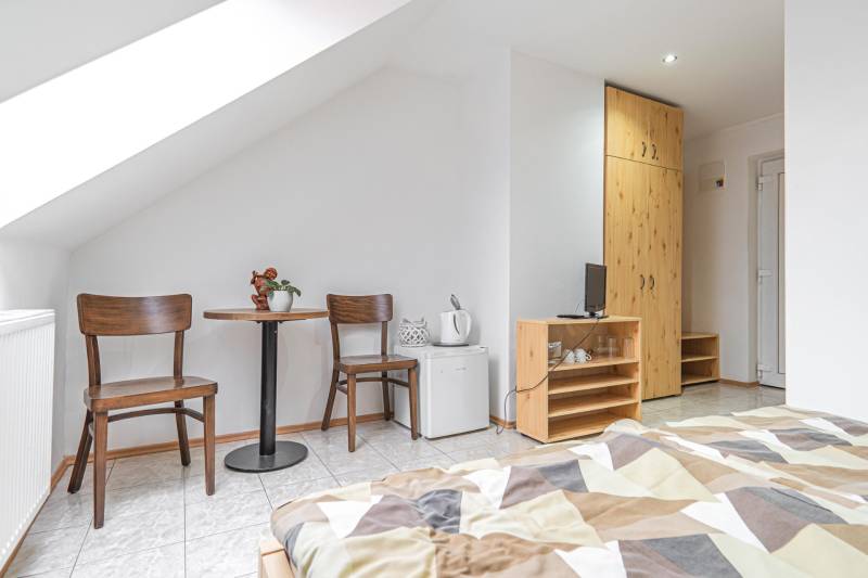 Predaj Exkluzívna ponuka elegantného penziónu s hostincom - Izba v Hotely a penzióny s dvojicou stoličiek, stolom, skriňou a posteľou.