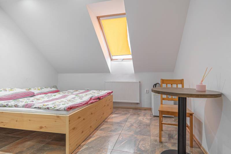 Predaj Exkluzívna ponuka elegantného penziónu s hostincom - Izba v Hoteloch a penziónoch s dreveným stolom, kvetinovými obliečkami a šikmým oknom.