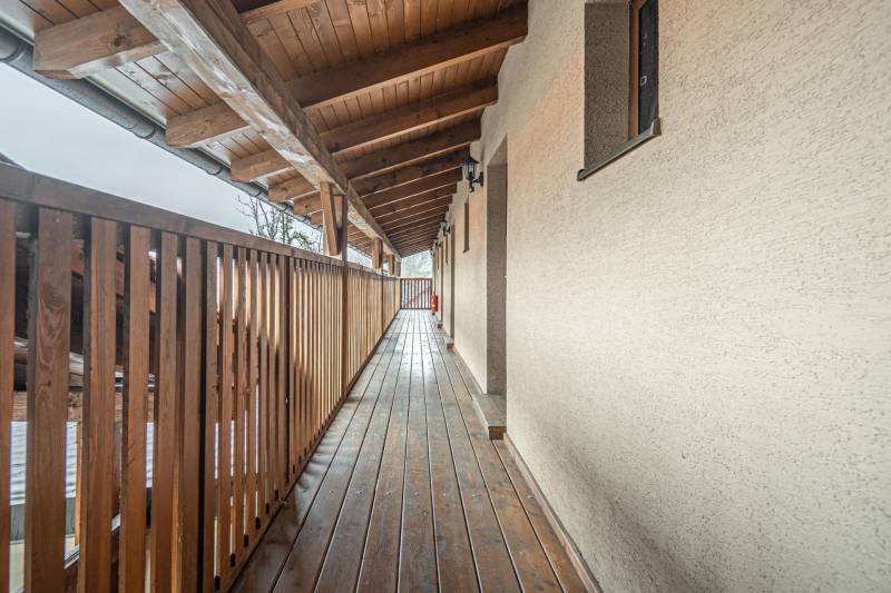 Predaj Exkluzívna ponuka elegantného penziónu s hostincom - Dlhá drevená chodba v Hotely a penzióny s dreveným stropom a zábradlím.