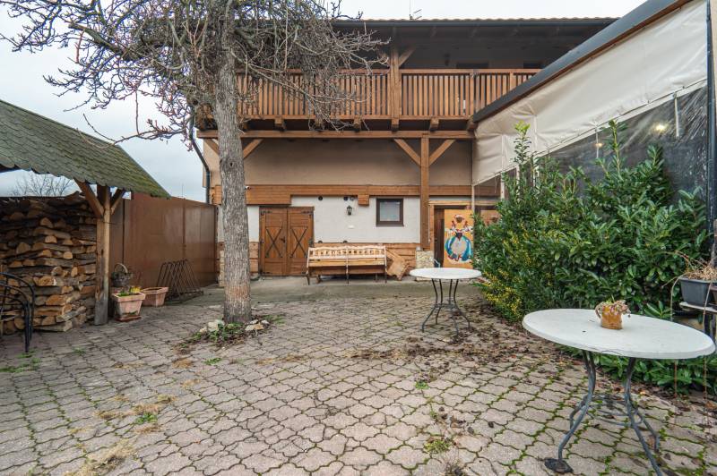 Predaj Exkluzívna ponuka elegantného penziónu s hostincom - Dvor penziónu na Hollého ulici, Holíč s drevenou terasou a stromom.