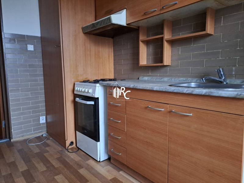 REZERVOVANÉ 2-izbový byt s nádherným výhľadom v pôvodnom stave   - Kuchyňa v 2-izbovom byte s dreveným dekorom podlahy a zabudovanými skriňami.