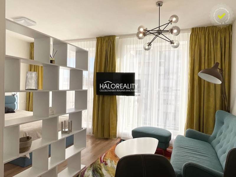 Prenájom, jednoizbový byt Banská Bystrica, Fončorda,... - Obývačka s presvetlenými závesmi, podlahou s dreveným dekorom a knižnicou v 1-izbovom byte.