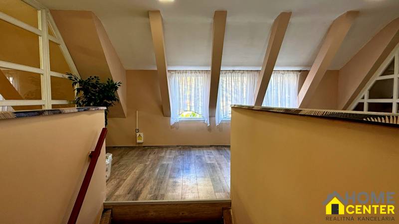 Na predaj unikátna dvojpodlažná budova na podnikanie aj bývanie - Interiér budovy s podlahou s dreveným dekorom, veľkým oknom a rastlinou.