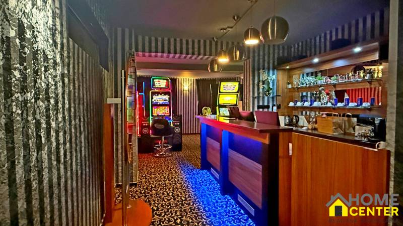 Na predaj unikátna dvojpodlažná budova na podnikanie aj bývanie - Interiér budovy s hracími automatmi, pultom a nápojmi na policiach.