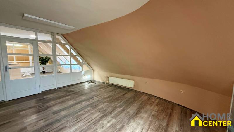 Na predaj unikátna dvojpodlažná budova na podnikanie aj bývanie - Interiér budovy s podlahou s dreveným dekorom a šikmou svetlohnedou stenou.