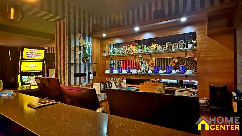 Na predaj unikátna dvojpodlažná budova na podnikanie aj bývanie - Interiér budovy s barovým pultom, ozdobnými regálmi a automatom.