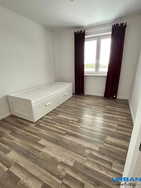 Praktický 3-izbový byt v súkromnej ulici v Šamoríne - Izba s posteľou, podlahou s dreveným dekorom a veľkým oknom v 3-izbovom byte.