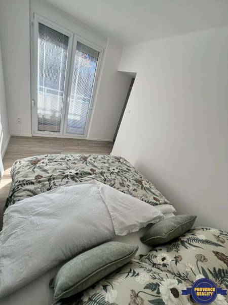 PREDAJ: 2 izbový tehlový byt-komplet.rek. - KOMÁRNO - Svetlá spálňa v 2-izbovom byte s dekoračnými vankúšmi a podlahou s dreveným dekorom.