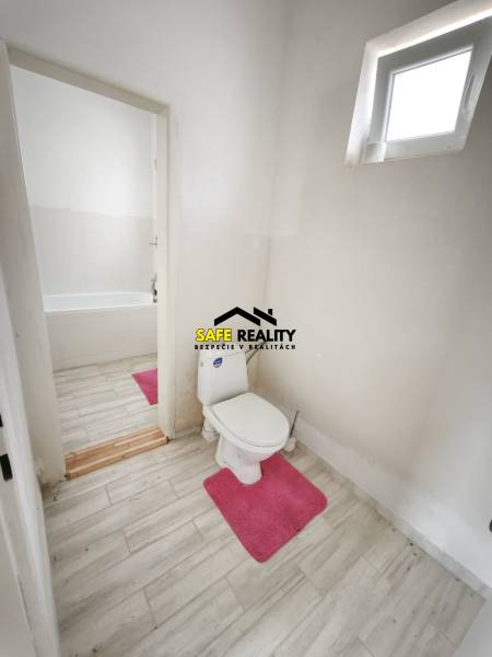 Rodinný dom - Lúčnica nad Žitavou  - Kúpeľňa v rodinnom dome s toaletou, vaňou a podlahou s dreveným dekorom.