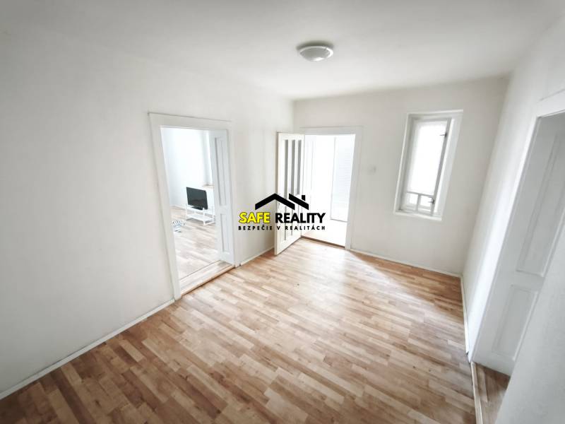 Rodinný dom - Lúčnica nad Žitavou  - Izba v rodinnom dome s podlahou s dreveným dekorom a jednoduchým zariadením.