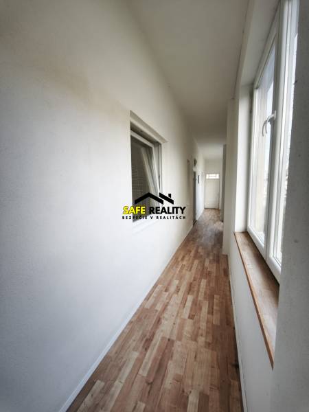 Rodinný dom - Lúčnica nad Žitavou  - Chodba v rodinnom dome s podlahou s dreveným dekorom a veľkými oknami.