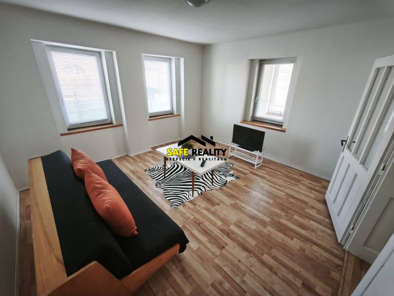 Rodinný dom - Lúčnica nad Žitavou  - Obývacia izba v rodinnom dome s pohovkou, televíziou a podlahou s dreveným dekorom.