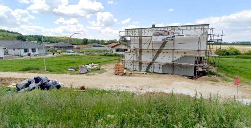 ***NOVÁ CENA***Stavebný pozemok 591m2 v novej lokalite, Modrovka - Stavebný pozemok na bývanie v Modrovke s rozostavanou budovou a okolím v pozadí.