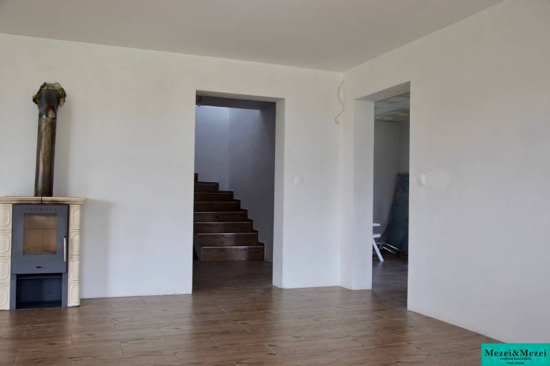 Na predaj – veľkorysý rodinný dom s úžasným výhľadom a pozemkom - Interiér rodinného domu s krbom, schodiskom a podlahou s dreveným dekorom.