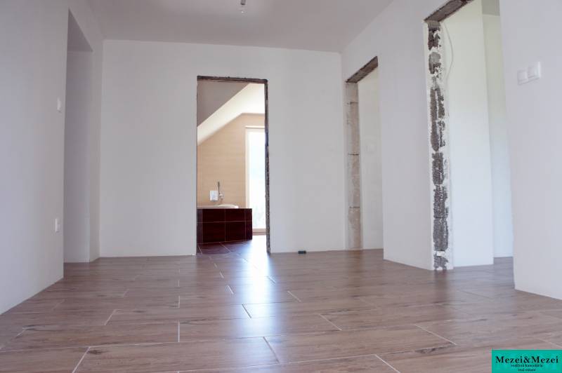 Na predaj – veľkorysý rodinný dom s úžasným výhľadom a pozemkom - Interiér rodinného domu s podlahou s dreveným dekorom a nezakrytými stavebnými otvormi.