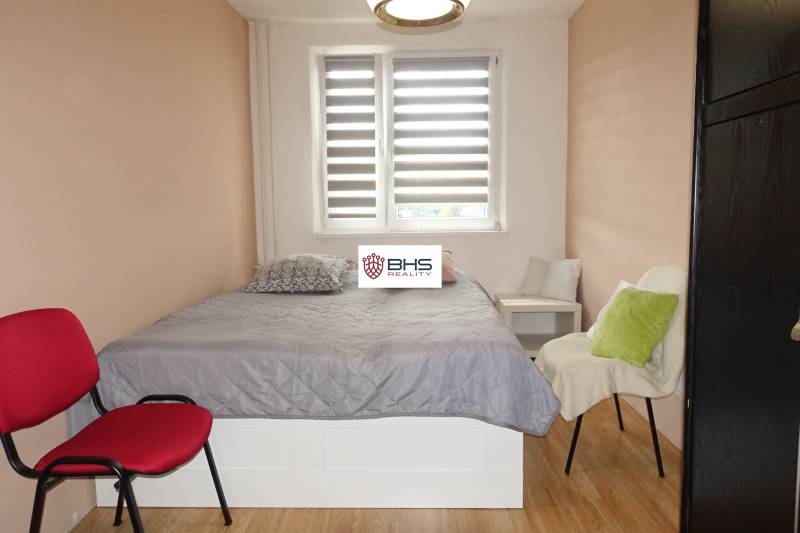 PREDAJ- 3-iz. byt, Homolova - Dúbravka, 67 m2, 11./12. posch., lodžia - Spálňa v 3-izbovom byte s posteľou, kreslami a podlahou s dreveným dekorom.