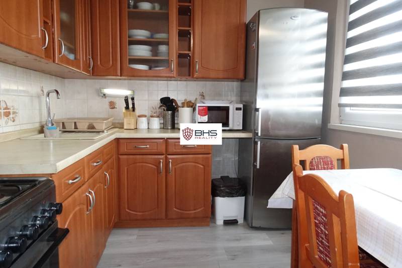 PREDAJ- 3-iz. byt, Homolova - Dúbravka, 67 m2, 11./12. posch., lodžia - Kuchyňa s dreveným dekorom, sporákom, chladničkou a jedálenským stolom v 3-izbovom byte.