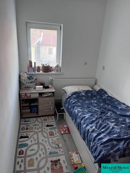 Na predaj moderný 4-izbový byt s veľkou terasou a súkromnou záhradou - Detská izba s posteľou, oknom a koberečkom v 4-izbovom byte.