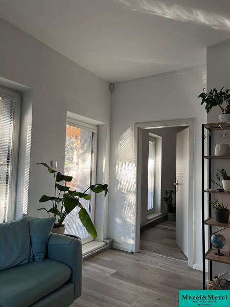 Na predaj moderný 4-izbový byt s veľkou terasou a súkromnou záhradou - Svetlá obývacia izba s rastlinami, sedačkou a podlahou s dreveným dekorom v 4-izbovom byte.